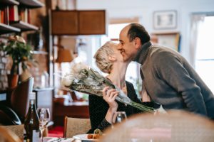 woman holding bouquet of flowers kissing a man